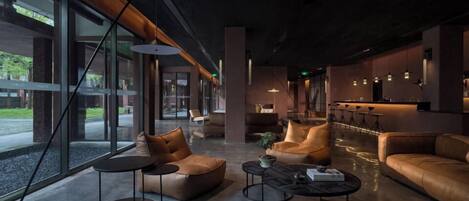 Ein moderner Lounge-Bereich mit Ledersofas, runden Tischen und einem großen Fenster mit Blick ins Freie.