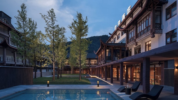 A pool area with lounge chairs, a reflection pool, and traditional architecture. - FunGee S Hotel Zhangjiajie National Park (Zhangjiajie)