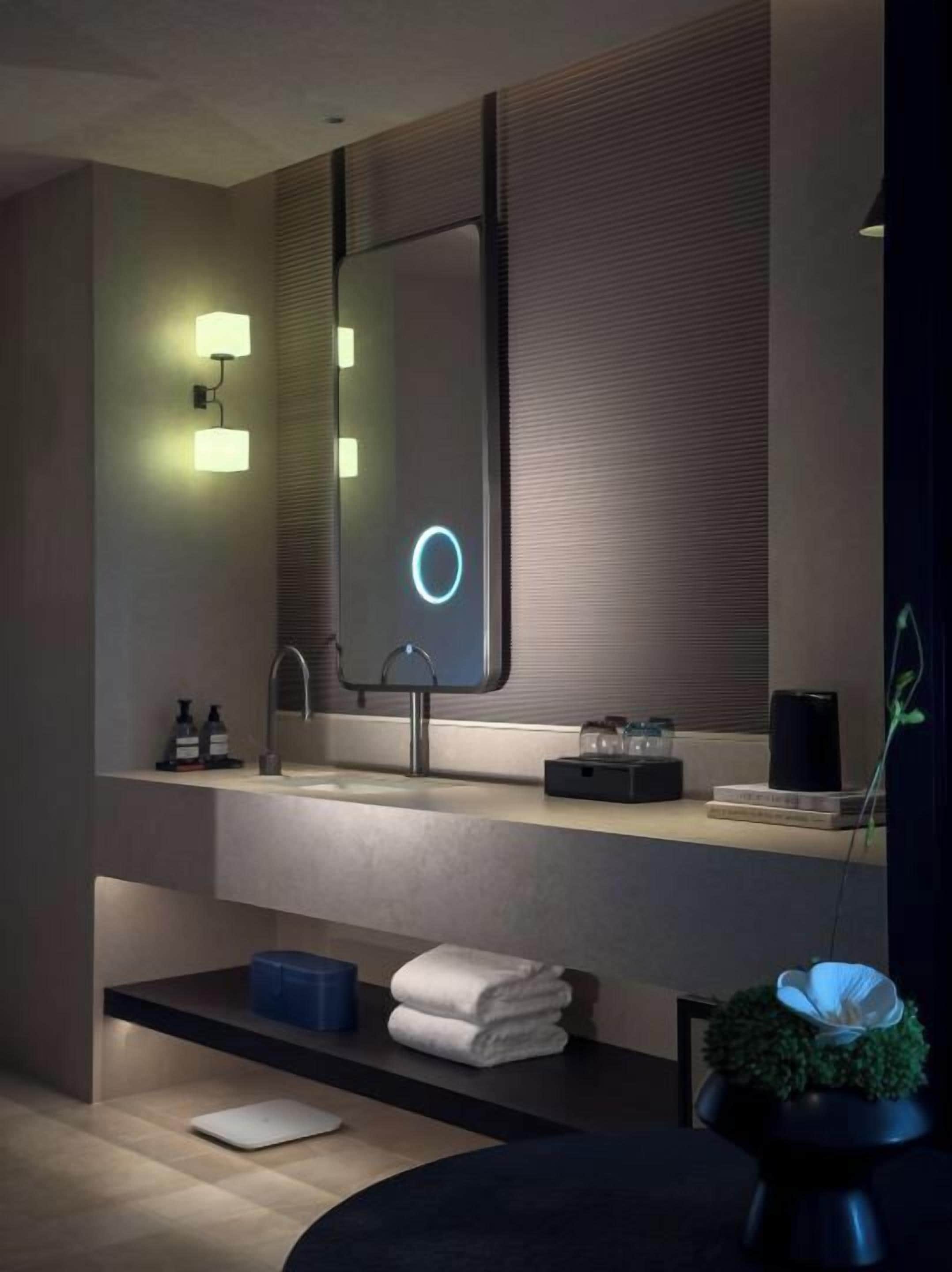 Un baño moderno con un espejo grande, un lavabo y un perchero para toallas.
