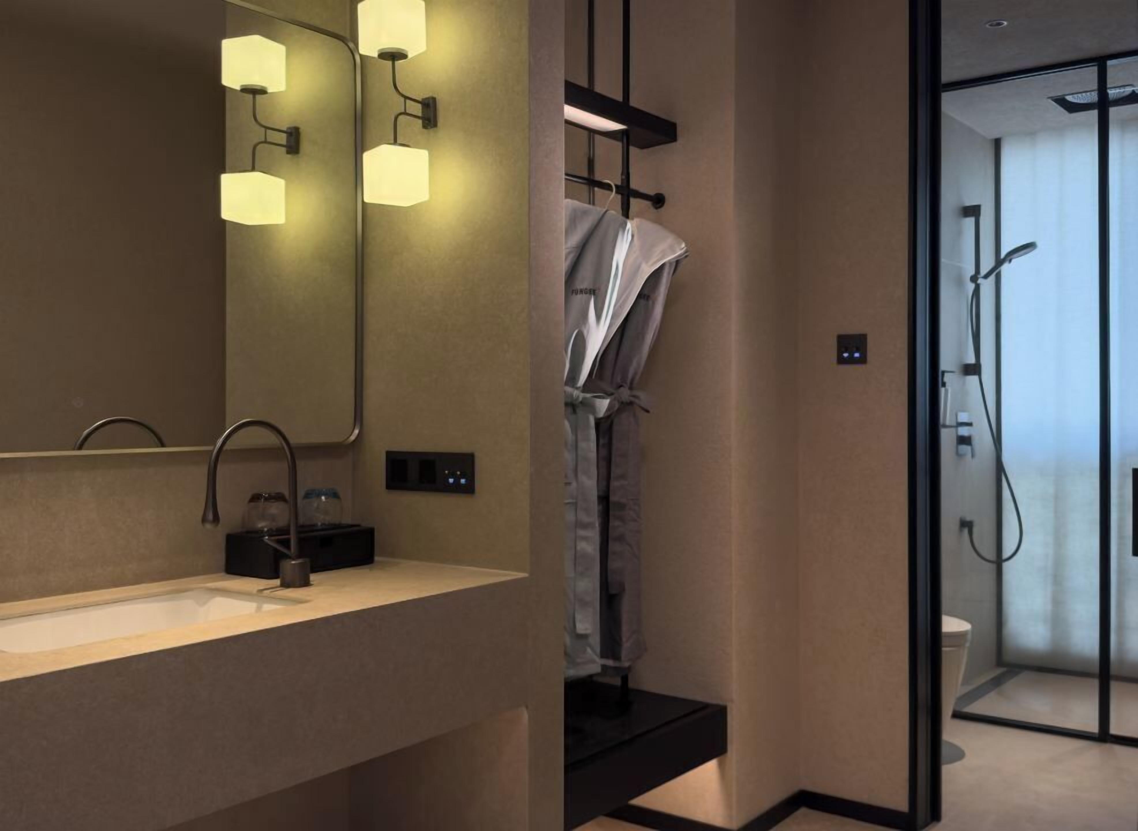 A modern bathroom with a large mirror, a sink, and a shower area.