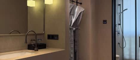 A modern bathroom with a large mirror, a sink, and a shower area.