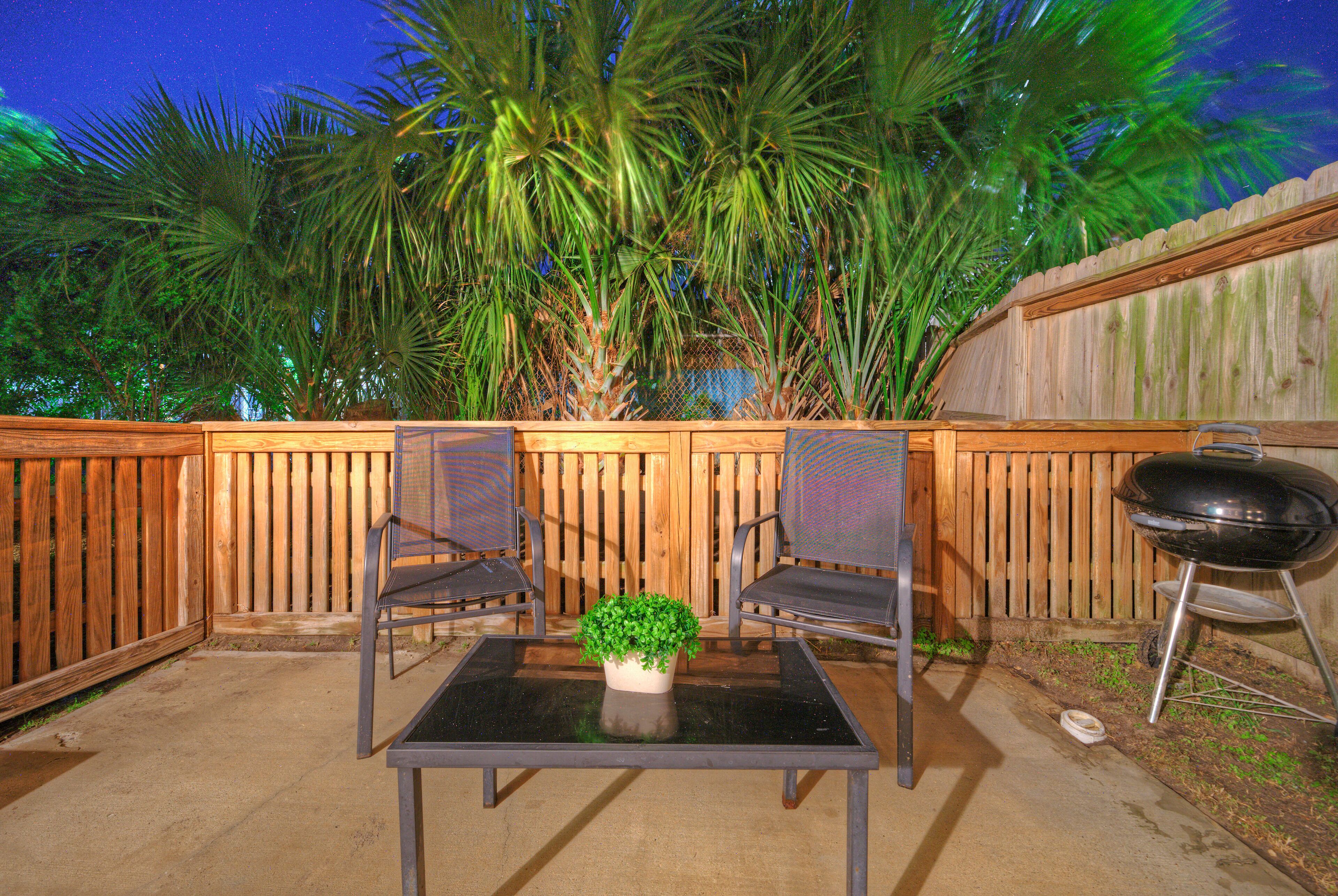 Eine Terrasse im Freien mit zwei Stühlen, einem Tisch, einem Grill und einem Holenzaun.