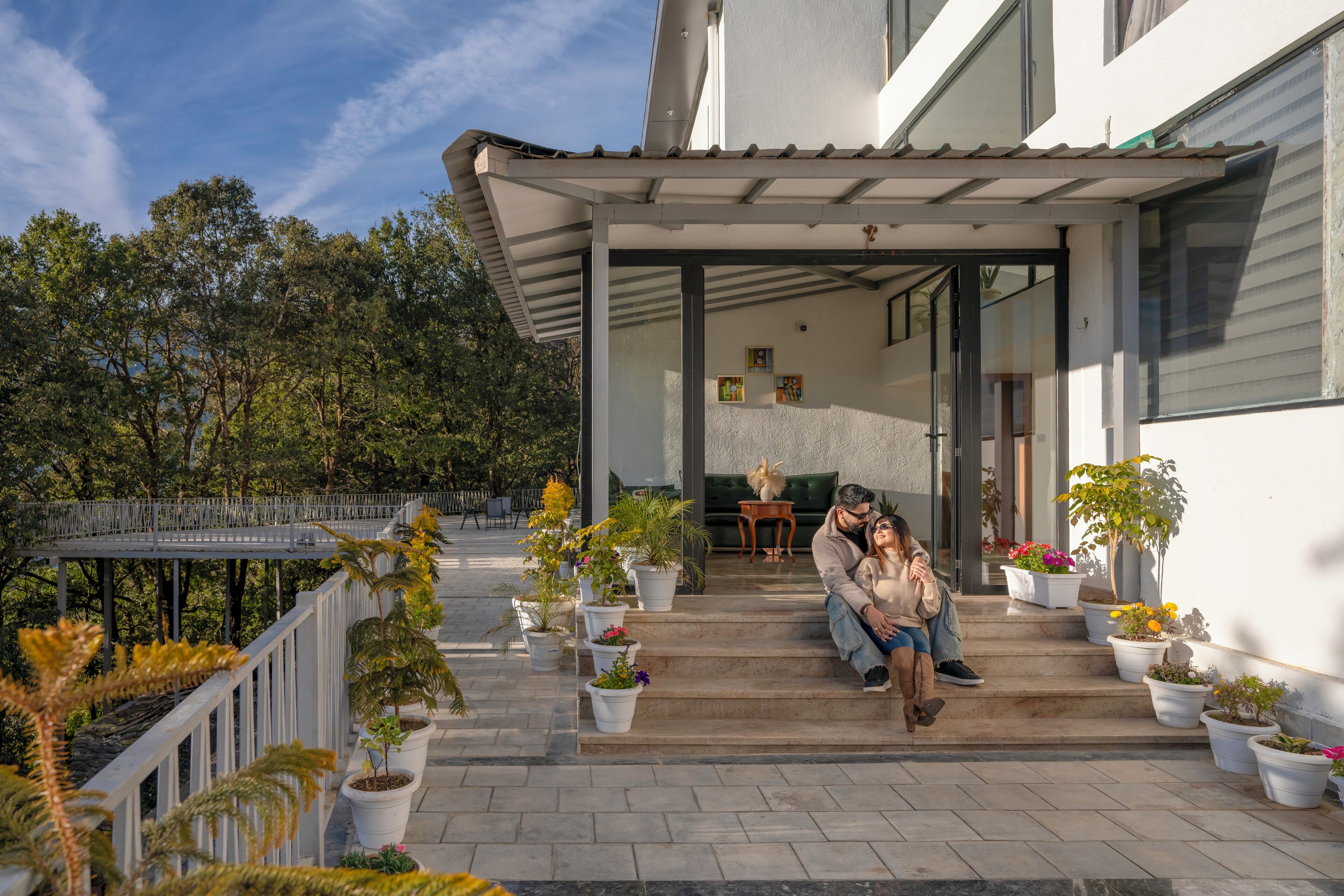 Une maison moderne dotée d’un porche abrité, d’un espace salon extérieur et de plantes en pot.