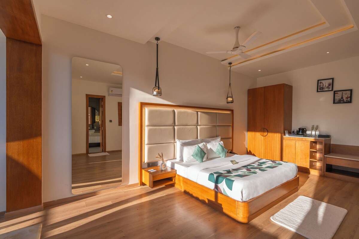 A modern bedroom with a large bed, wooden flooring, a ceiling fan, and a built-in wardrobe.