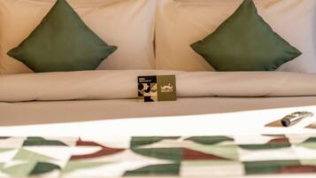 A bed with two pillows, a welcome card, and a remote control.