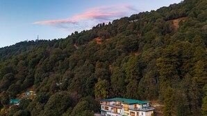 A multi-story building with a green roof, surrounded by dense forest. - Moustache Select Nainital (Nainital, Uttarakhand)
