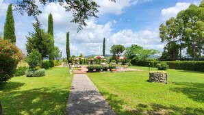 Um jardim com caminho pavimentado, área de estar externa e uma construção de pedra.