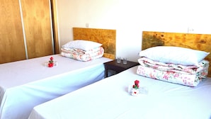 Two single beds with wooden headboards, white bedding, and floral-patterned blankets. - Chinese guesthouses in Casablanca (Casablanca)