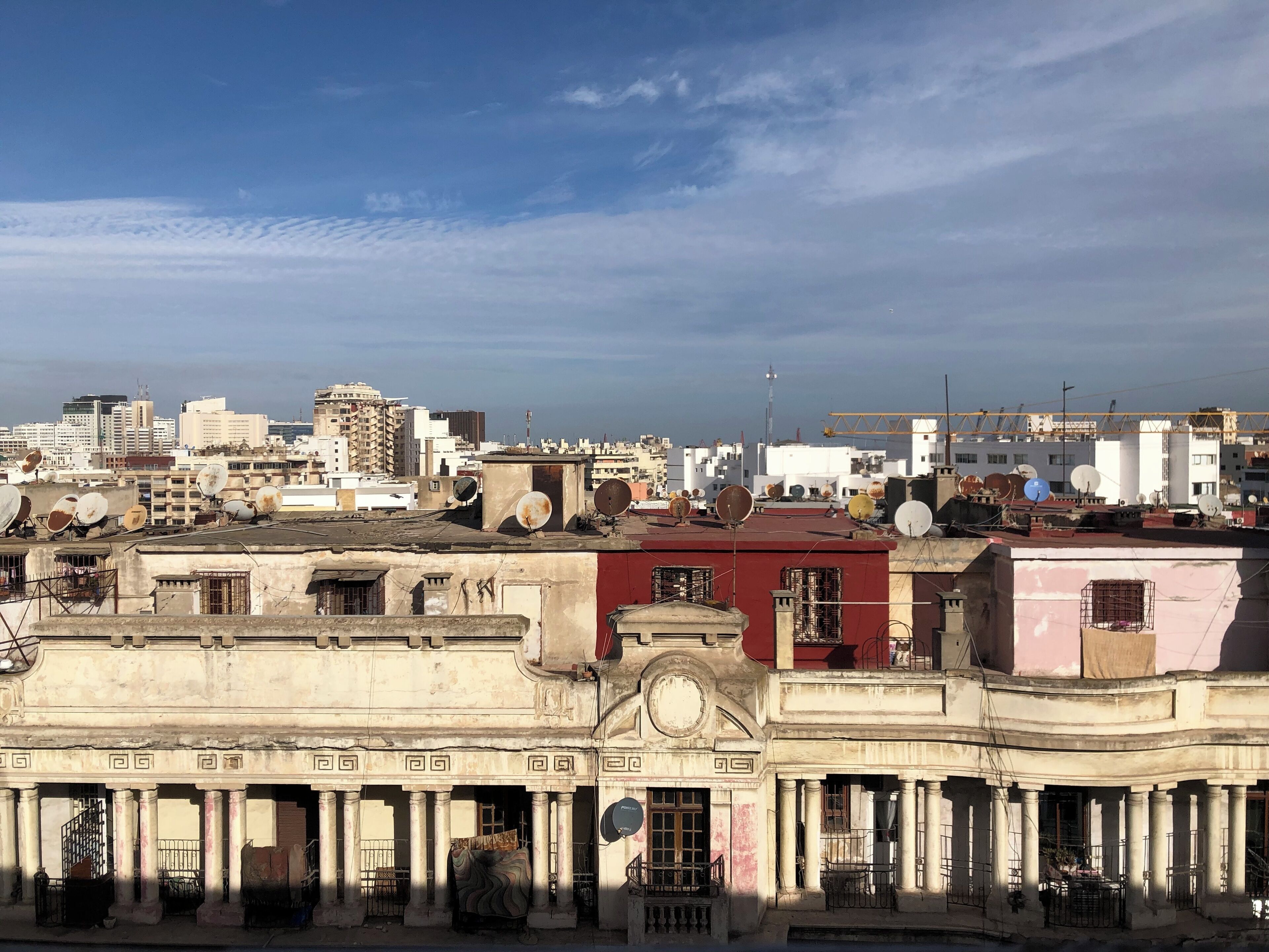 A cityscape with a mix of modern and historical buildings, including a prominent building with classical columns and a red facade.