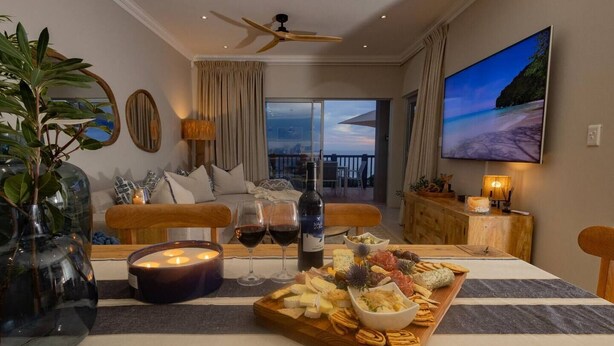 A cozy living room with a wooden coffee table, a TV, and a balcony with a scenic view.