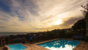 A rectangular pool with a stone border, surrounded by a wooden fence and a wooden deck.