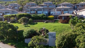 A residential area with multiple two-story houses, a grassy lawn, and a sign labeled "Sheer Cliffs".
