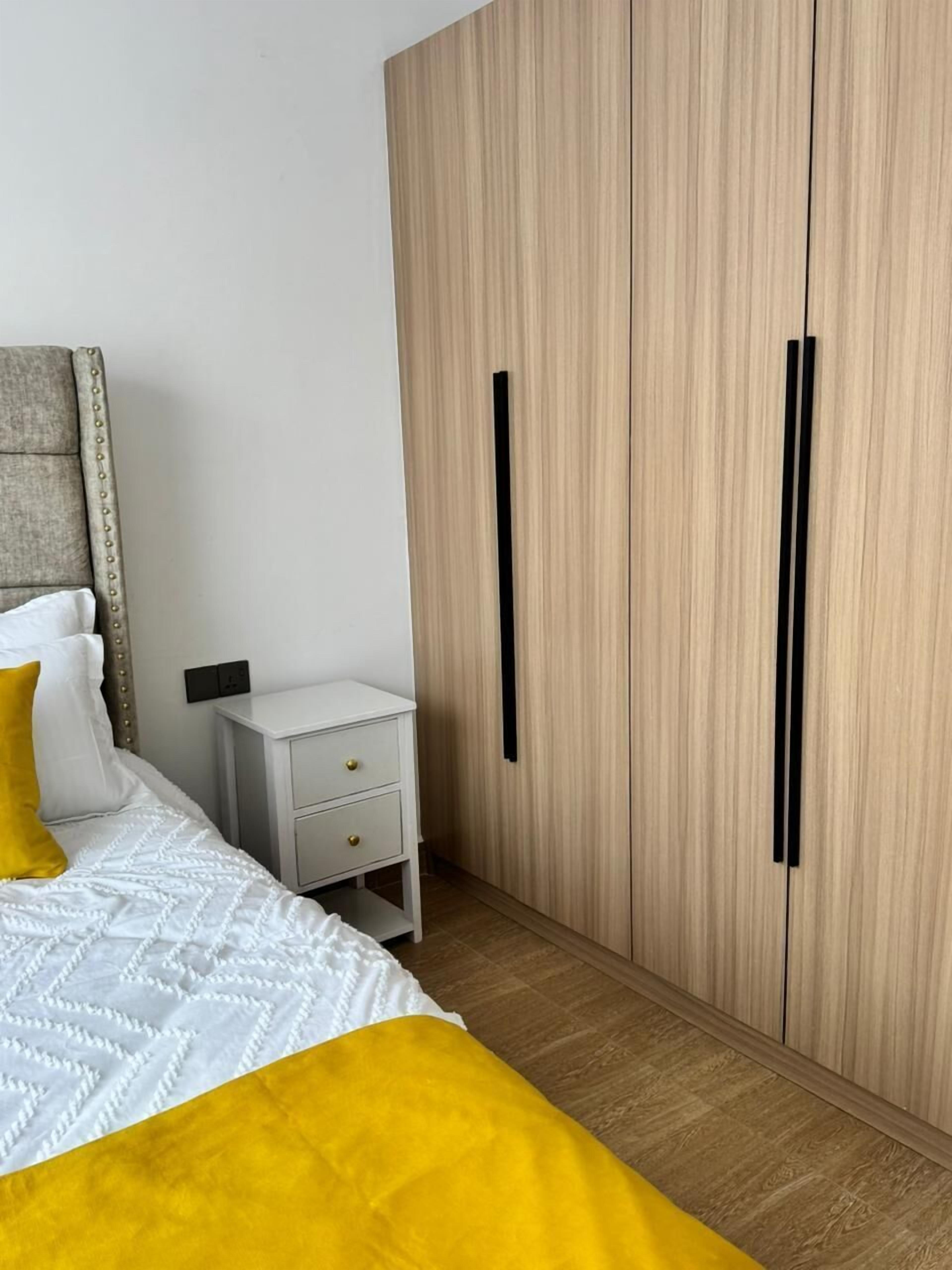 A bedroom with a bed, bedside table, and a wardrobe.