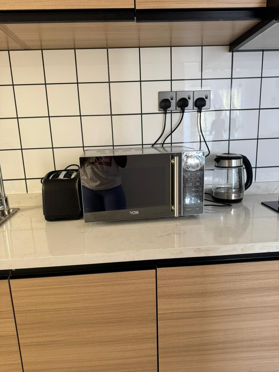 Cozinha com micro-ondas, torradeira e cafeteira sobre o balcão.