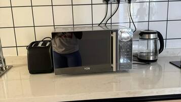 Cozinha com micro-ondas, torradeira e cafeteira sobre o balcão.