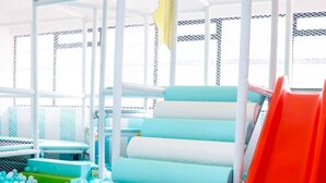 Ein Kinderspielbereich mit Rutsche, Treppen und einem Ballbecken.