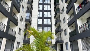 A modern multi-story building with balconies, a central courtyard with a palm tree, and a clear sky. - The Loftel Ruaka (Ruaka)