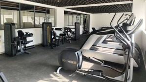 Ein Fitnessraum mit Cardiogeräten, Kraftmaschinen und einer Spiegelwand.
