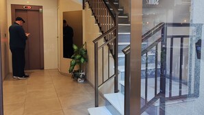 Eine Hotelhalle mit Treppe, Rezeption und einer Zimmerpflanze.