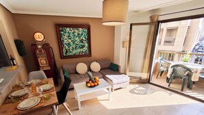 Ein Wohnzimmer mit einer Couch, einem Esstisch und einem Balkon mit Stühlen.