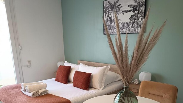Quarto moderno com cama, mesa de cabeceira e mesa redonda com cadeiras.