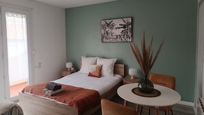 Um quarto com cama, mesas de cabeceira, uma mesinha redonda e uma cadeira.