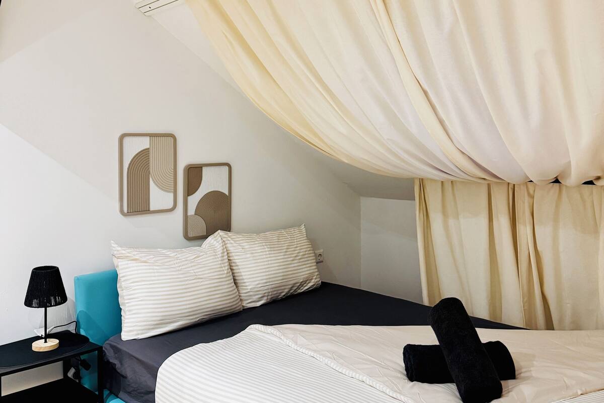 A modern bedroom with a bed, a nightstand, a lamp, and wall art.