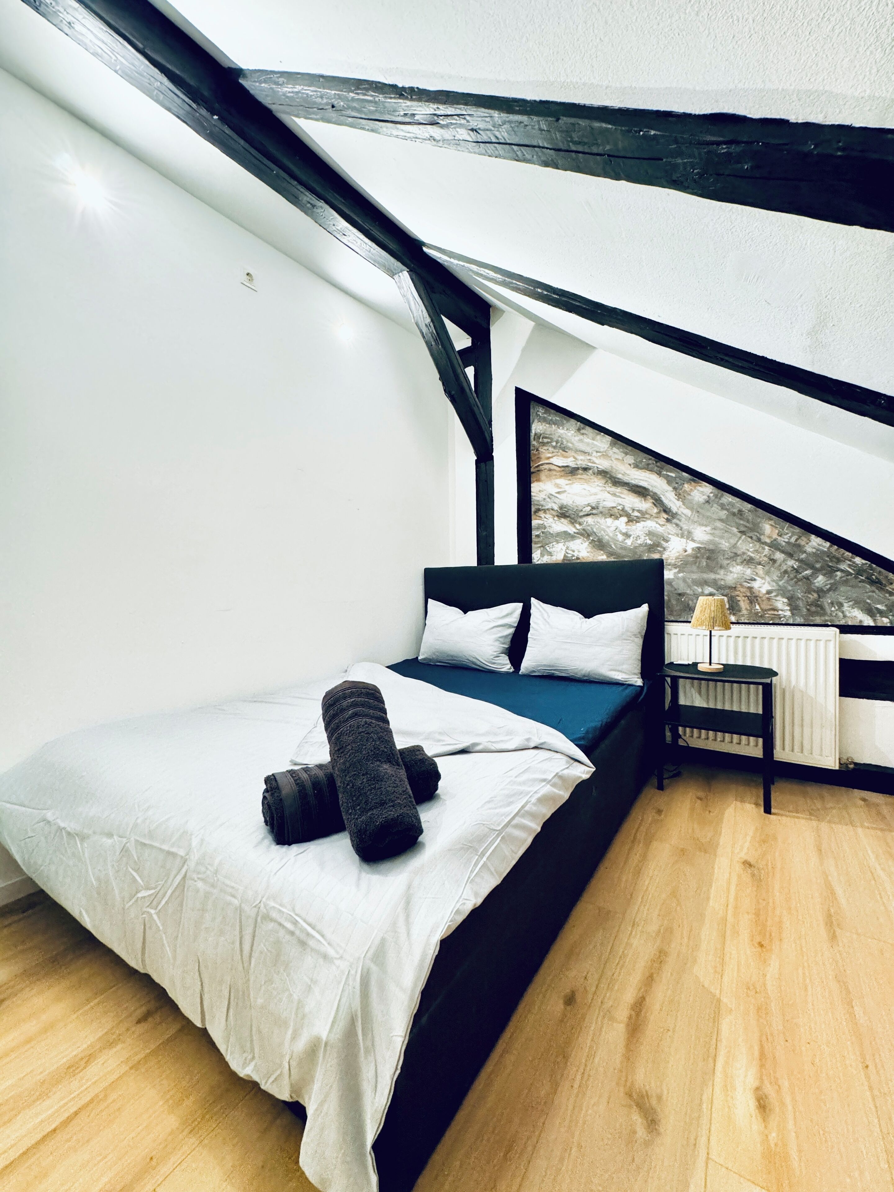 A bedroom with a bed, a nightstand, and a window with a view.