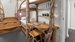 Een kleine kamer met een stapelbed, een houten bureau, een stoel en een laptop.
