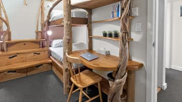A compact room with a bunk bed, a wooden desk, a chair, and a laptop.
