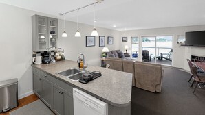 Een moderne keuken met een vaatwasser, een dubbele spoelbak en een eethoek met een tafel en stoelen.