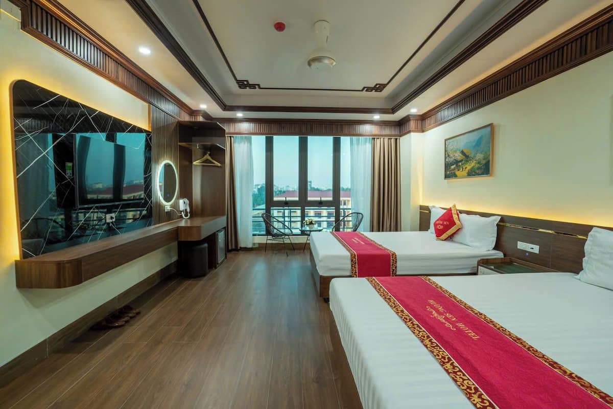 Une chambre d’hôtel avec deux lits, une télévision, un balcon avec vue et une grande fenêtre.