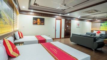 A hotel room with two beds, a sofa, a ceiling fan, and artwork on the walls.