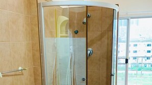 A modern bathroom with a glass-enclosed shower, a toilet, and a sink. - Sea Prestige (Pattaya)