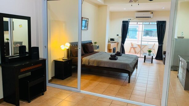 A modern hotel room with a large bed, a desk, a mirror, and a sliding door leading to a balcony. - Sea Prestige (Pattaya)