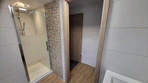 Casa de banho moderna com cabine de duche em vidro, um painel decorativo e porta de madeira.