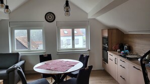 Uma cozinha moderna com área de jantar, janelas amplas e um relógio na parede.