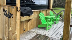 A wooden deck with a pergola, a bench, and a table with chairs. - Escape to Tranquillity: The Bus Stop Your Tiny Home Bus Retreat (Wainuiomata Coast)