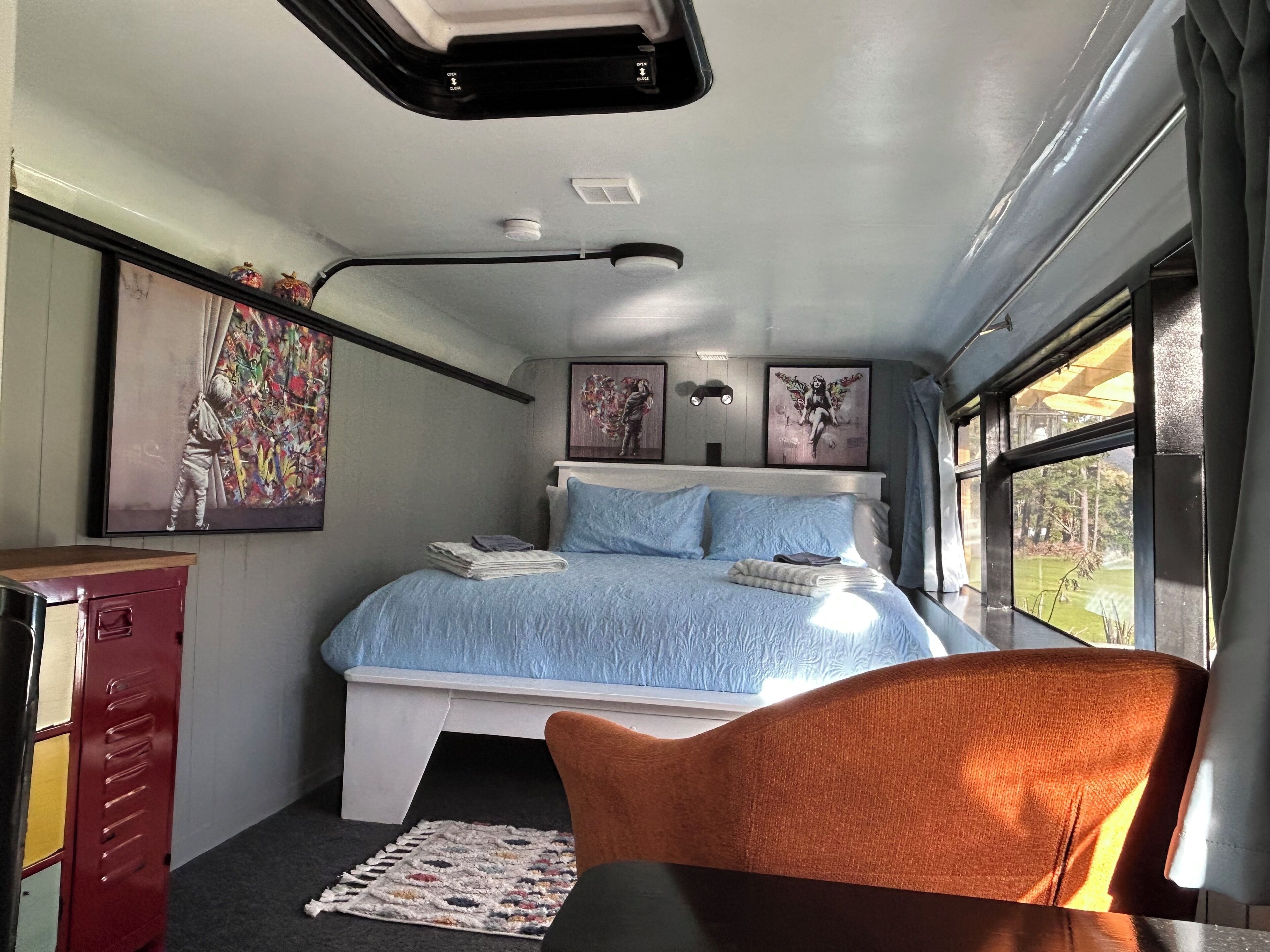 A bedroom with a bed, a desk, a chair, and a window.