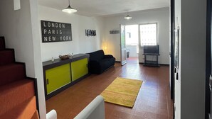 Amplia sala de estar con escaleras, un sofá, una isla de cocina y un comedor.