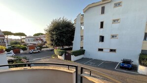 Zona residencial con un edificio blanco, un estacionamiento y un árbol.