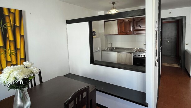 Una cocina moderna con estufa integrada, un área de comedor con mesa y sillas, y un amplio ventanal con vistas a la cocina.