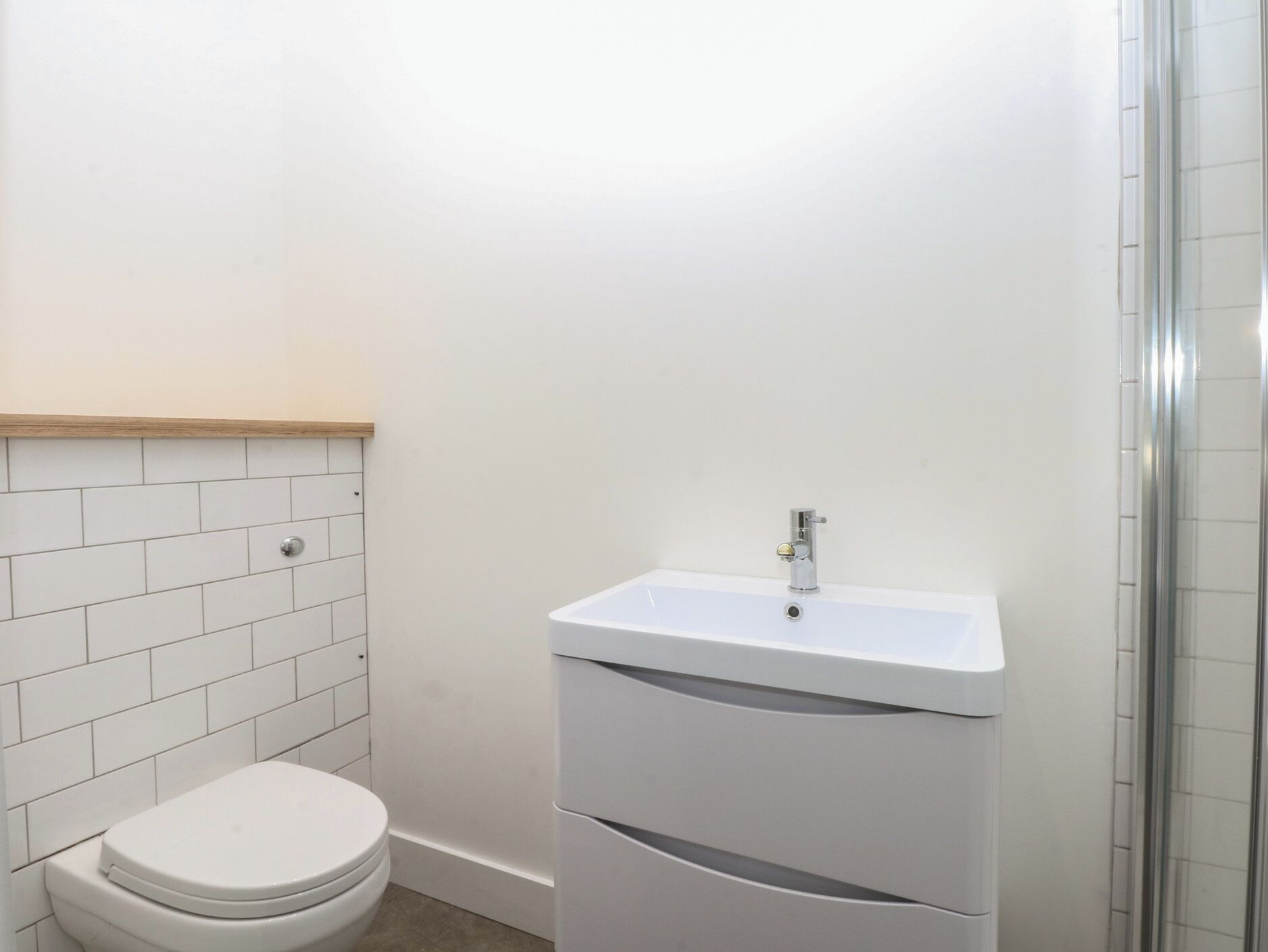 A bathroom with a white toilet, a sink with a mirror, and a shower area.