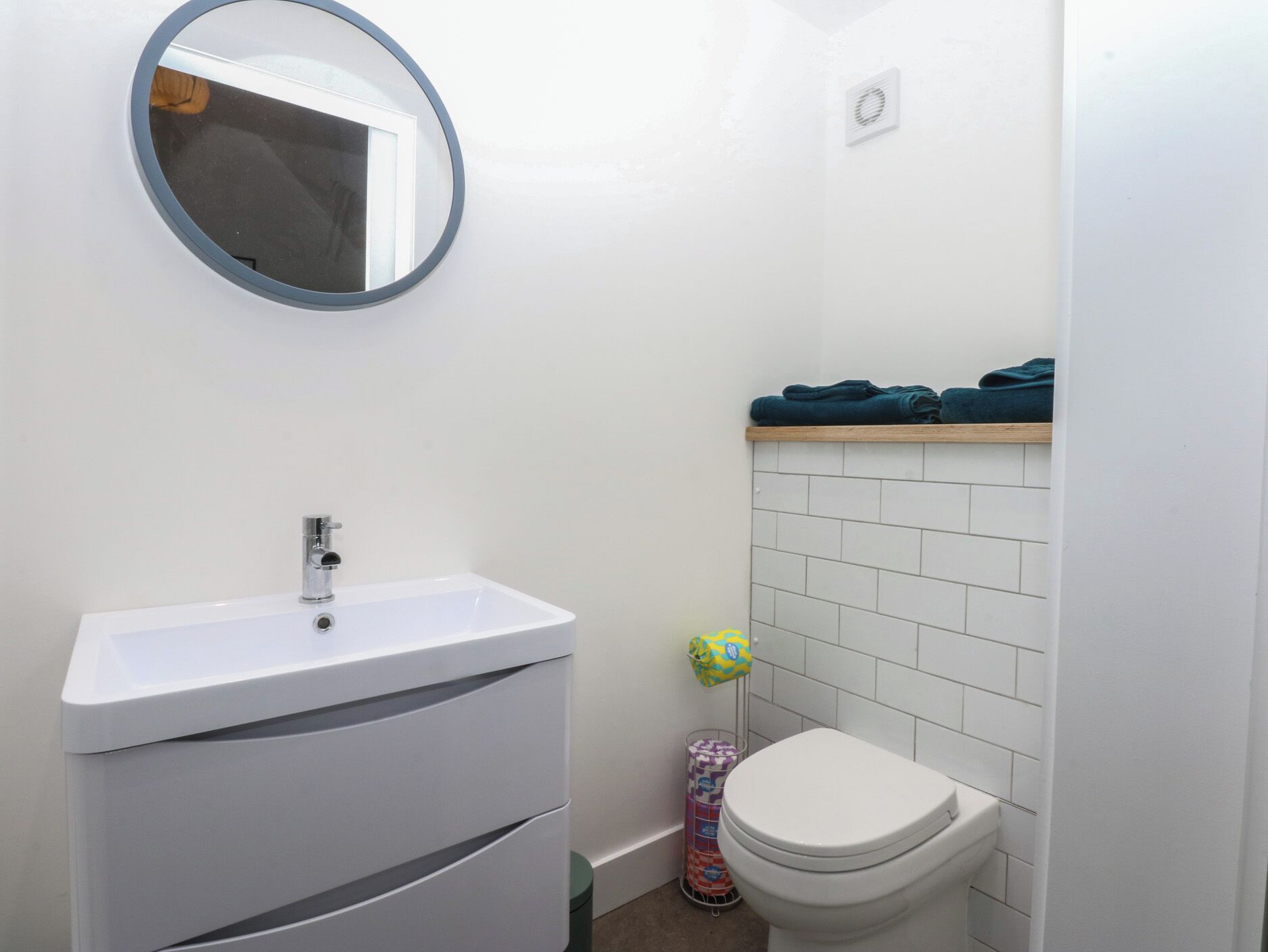 Un baño con un lavamanos blanco, un inodoro, un espejo y un perchero para toallas.