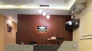 Ένας πάγκος υποδοχής με το λογότυπο της επιχείρησης, μια τηλεόραση και ένα δάπεδο με σχέδιο που μιμείται το μάρμαρο.