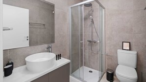 Une salle de bain moderne avec une douche à parois de verre, un lavabo blanc et des toilettes.
