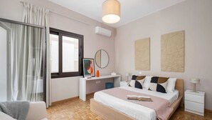 A modern bedroom with a bed, bedside tables, a desk, a chair, a window with curtains, and artwork on the walls. - Casa Centrale by Nomads (Paphos)