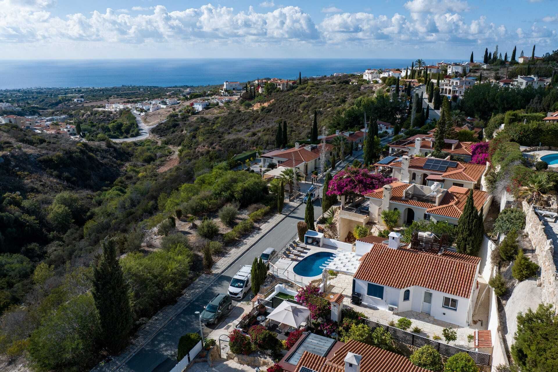 A coastal residential area with houses, a swimming pool, and a view of the sea.