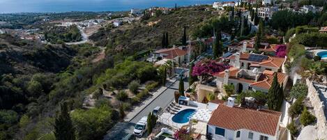 A coastal residential area with houses, a swimming pool, and a view of the sea.