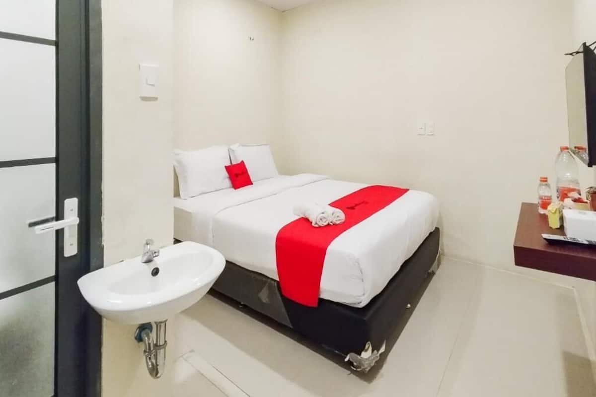 Ein Hotelzimmer mit Bett, Nachttisch, Waschbecken und Spiegel.